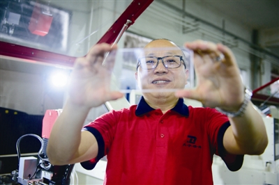 大宇精雕的董事长雷万春展示精雕工艺生产的手机玻璃盖板 大宇精雕的董事长雷万春展示精雕工艺生产的手机玻璃盖板